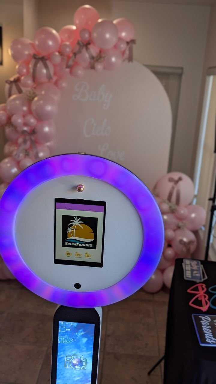 A SoCalFun365 photo booth with a ring light and iPad, set up against a pink balloon arch at a baby shower in Orange County